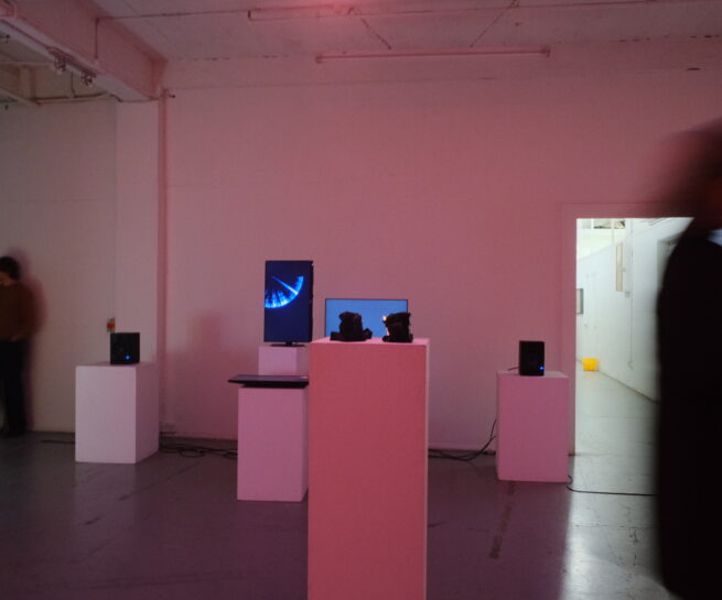 The exhibition view. In front 3D sculptures. In the background 3 screens having a generated artwork