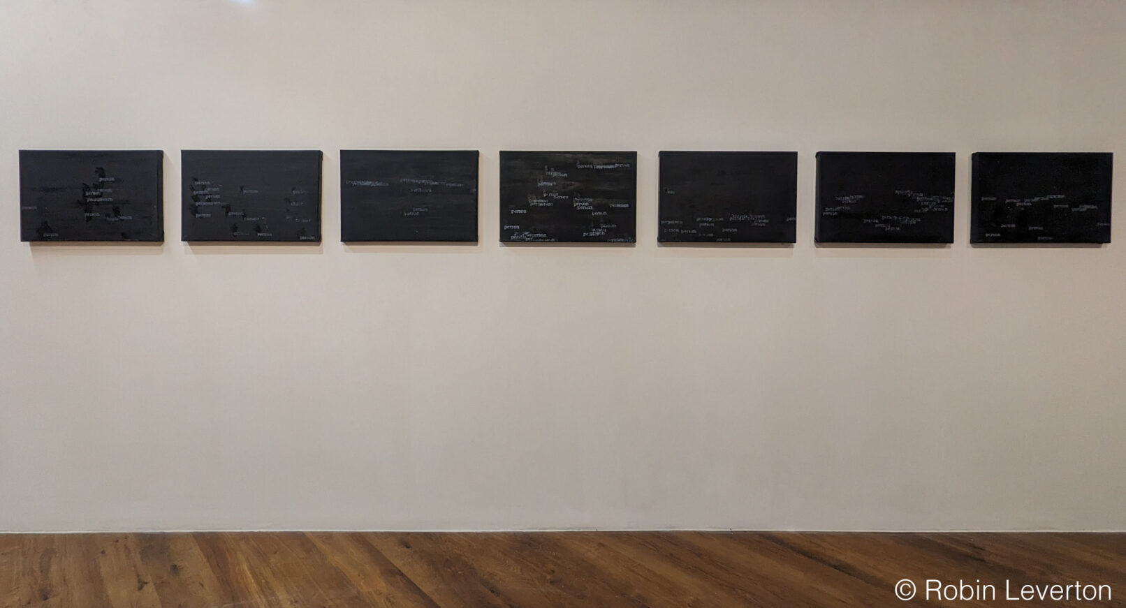 seven black paintings on a gallery wall