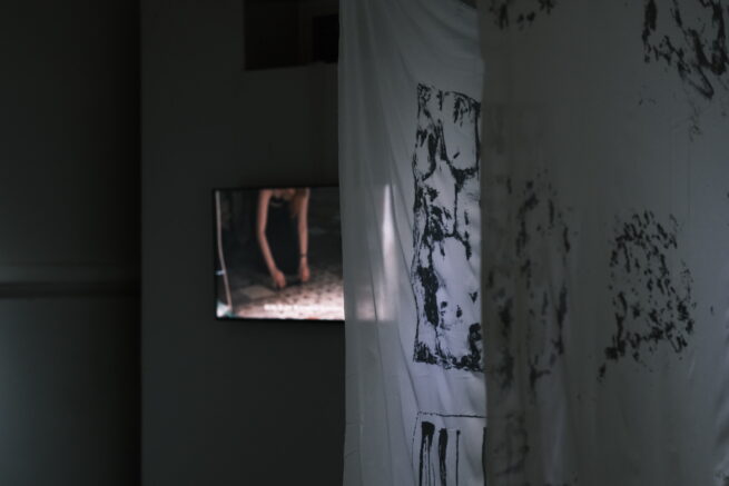 art installation with printed textile in front and a screen on the back