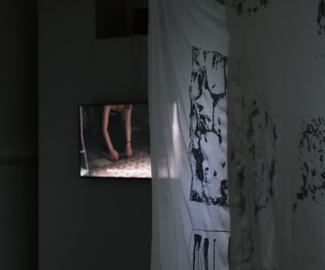 art installation with printed textile in front and a screen on the back