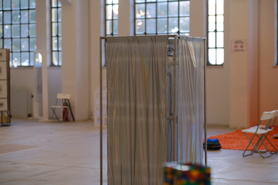 shiny textile surrounds a metal structure in a large gallery.