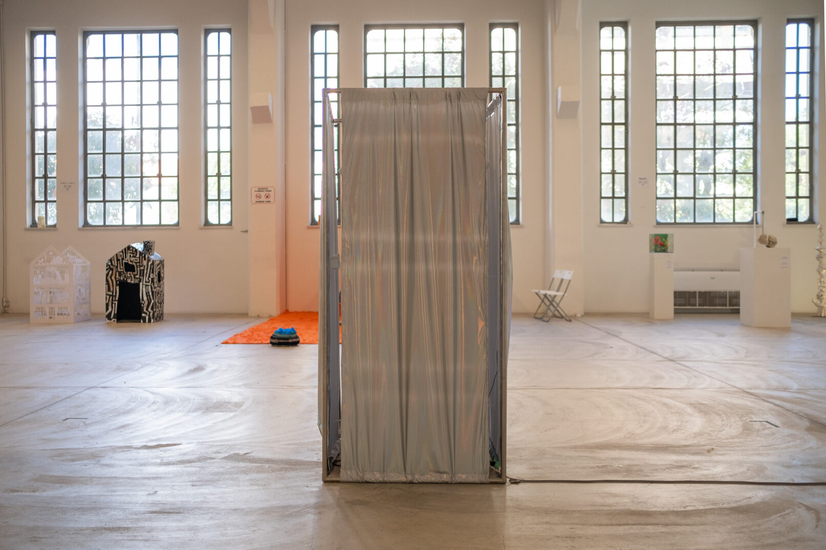 shiny textile surrounds a metal structure in a large gallery.