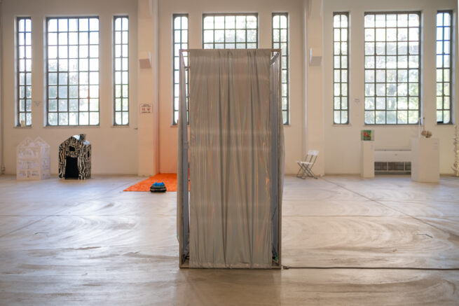 shiny textile surrounds a metal structure in a large gallery.