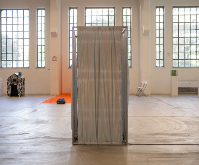 shiny textile surrounds a metal structure in a large gallery.