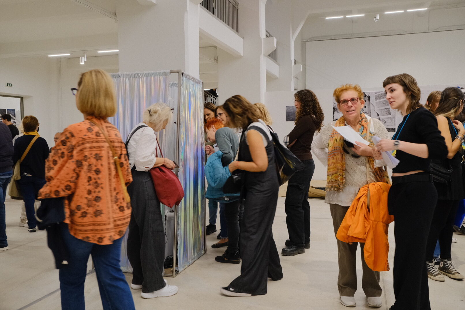People are viewing the work. shiny textile surrounds a metal structure in a large gallery.