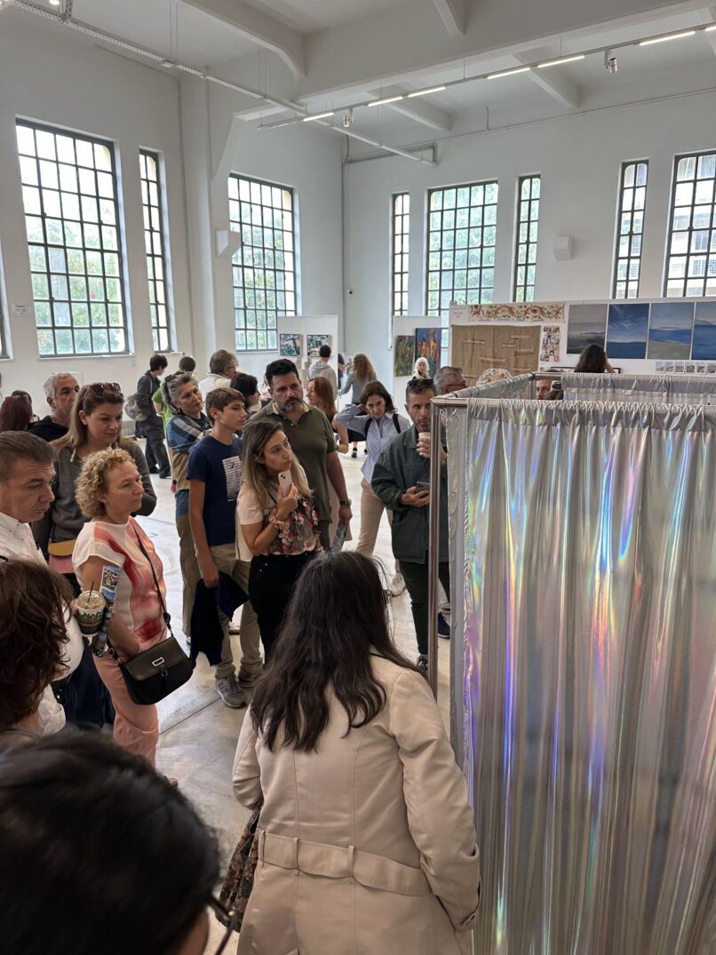 People are viewing the work. shiny textile surrounds a metal structure in a large gallery.